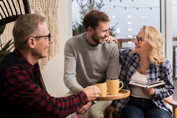Three people sitting together, laughing and drinking coffee, showcasing psycho moments from partners.