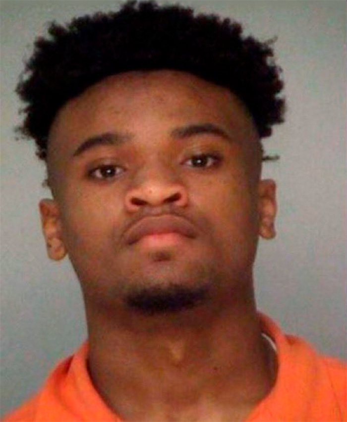 Mugshot of a young man with a fade haircut and goatee, implicated in a sibling dispute tragedy.