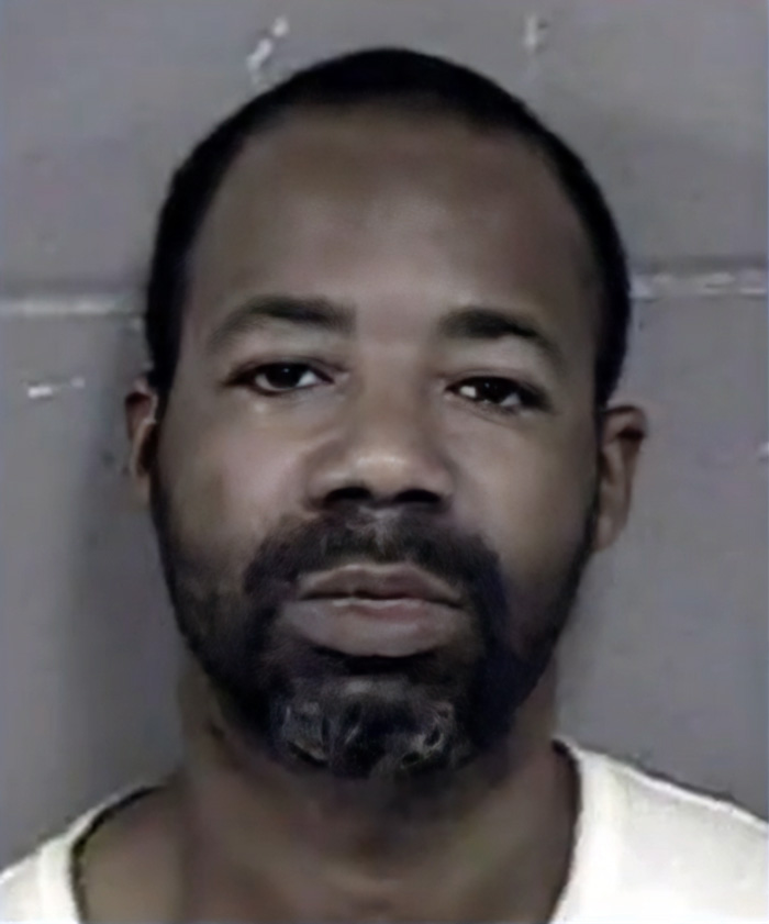 A man with a beard and short hair in a mugshot, symbolizing the severe consequences of sibling disputes and tragedy.
