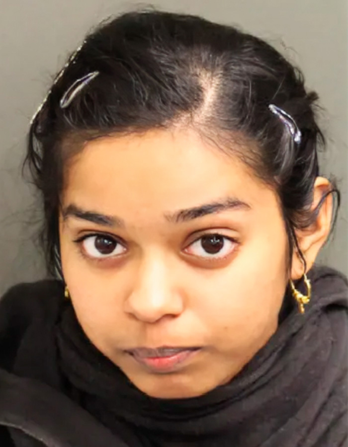 Mugshot of a young woman with dark hair and gold hoop earrings, involved in a sibling dispute.