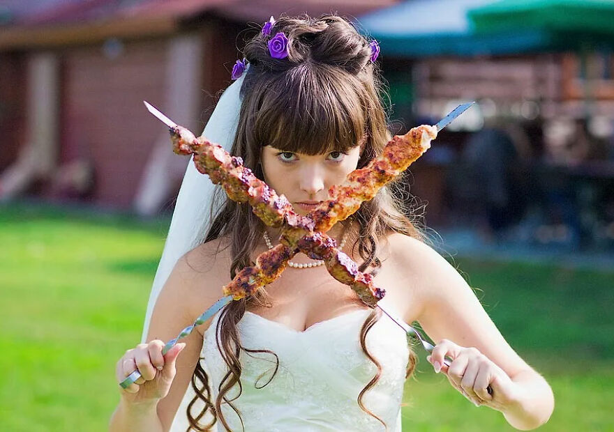 A bride holding two kebabs like swords in a silly wedding photo, making for a memorable moment.