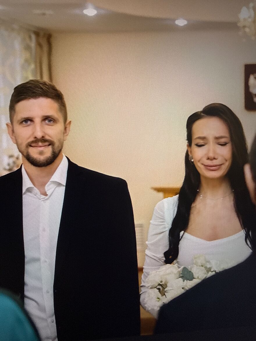 A silly wedding photo of a groom smiling while his bride stands beside him with a crying face.
