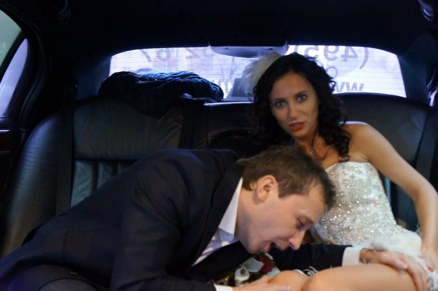 A groom bending down in a car with his bride in a funny wedding photo, creating a silly memory.