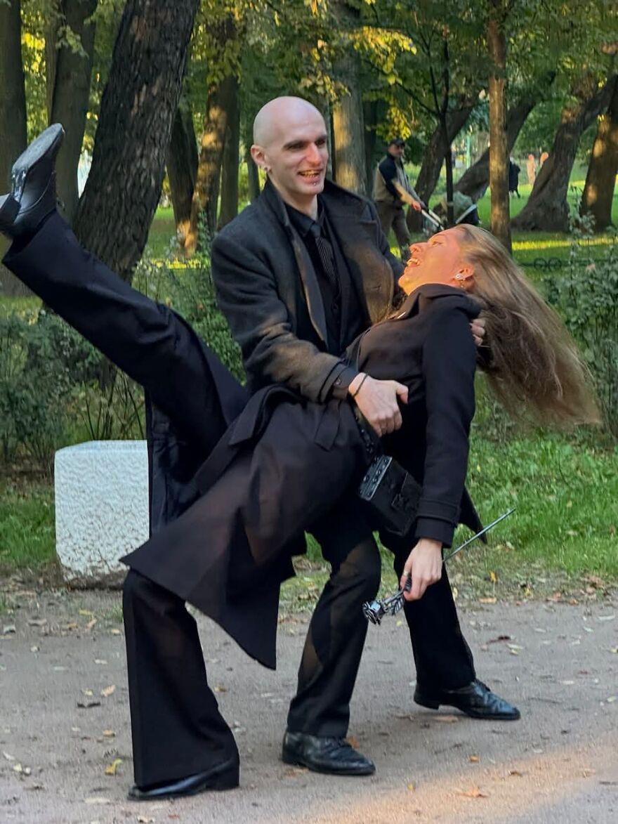 Silly wedding photo of a couple in black, with the man holding the woman in a playful pose.