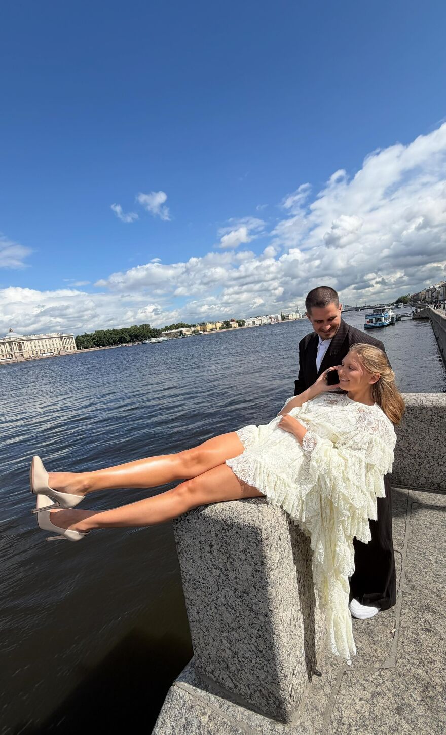 A happy couple on a bridge by the water, capturing a funny wedding photo.