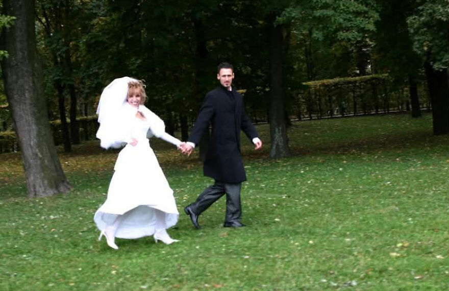 A happy bride and groom walking in a park, smiling for their wedding photos.