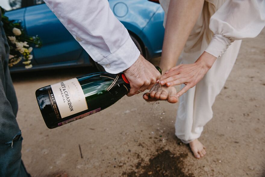 A man pouring champagne on a woman's bare feet, a funny wedding moment.