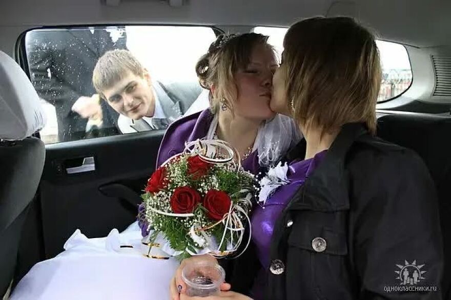A bride kissing another woman in a car, while a man looks in, a funny wedding photo.
