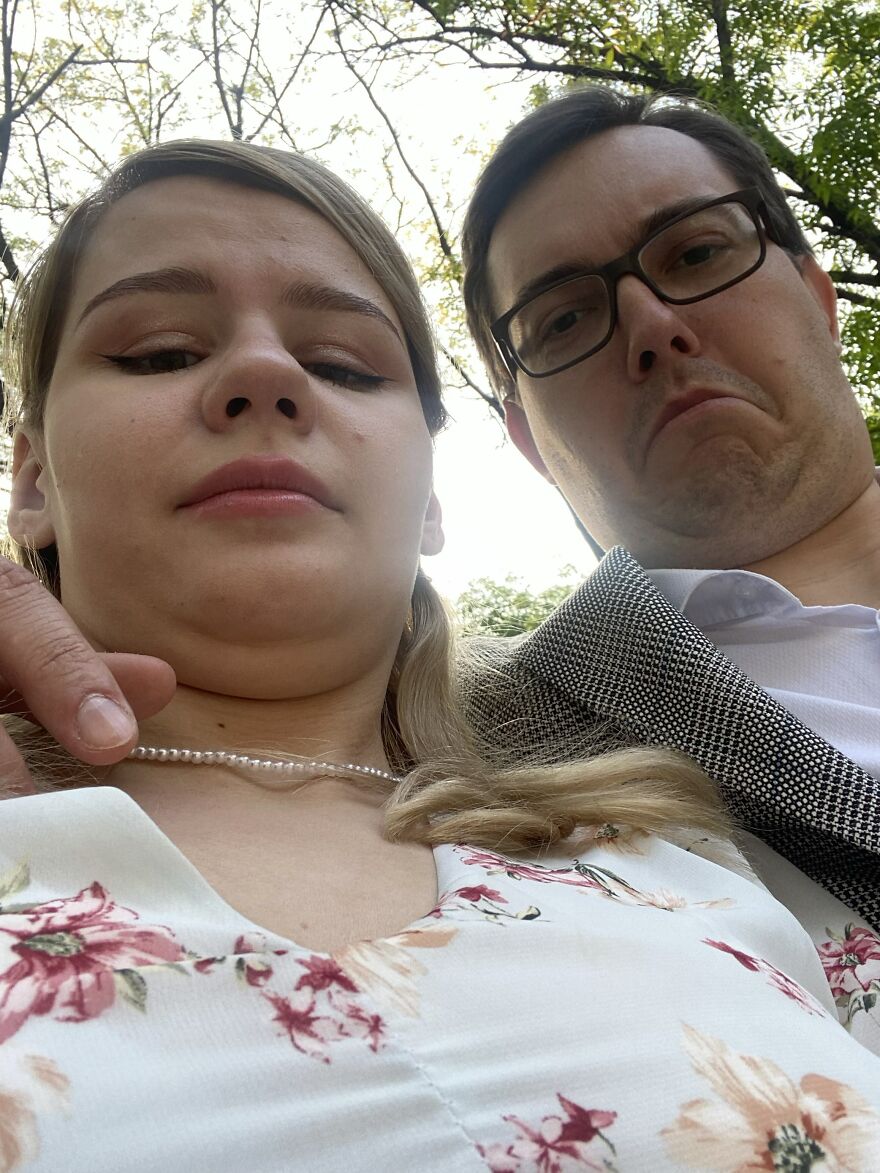 A couple taking a funny wedding selfie from a low angle, both making humorous faces for their wedding photo.