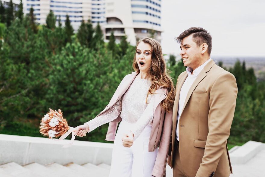 A bride with an open mouth expression and a groom looking sideways, capturing a funny wedding photo outdoors.