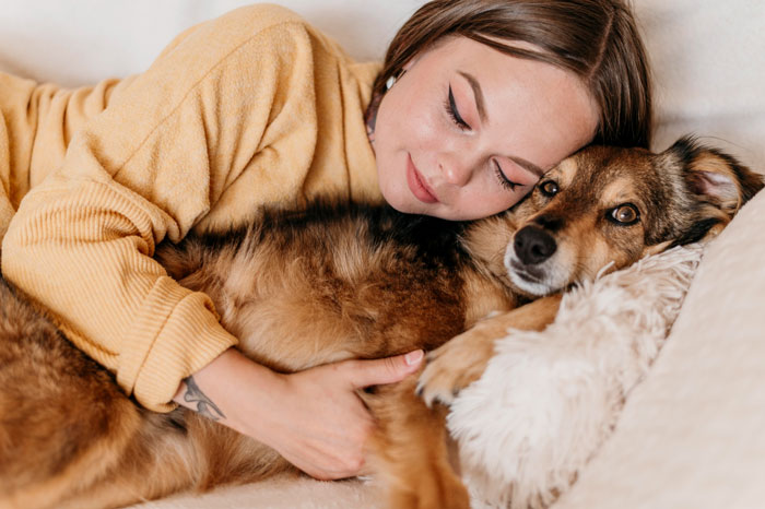 A woman boycotting her sibling's wedding, shown cuddling her service dog, banned from the event.