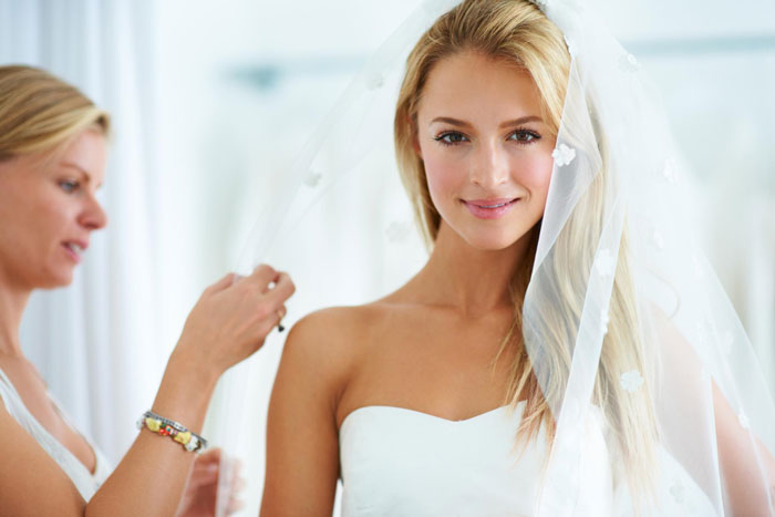 A beautiful bride smiling in her wedding dress and veil, focusing on the anxious sibling's wedding event.