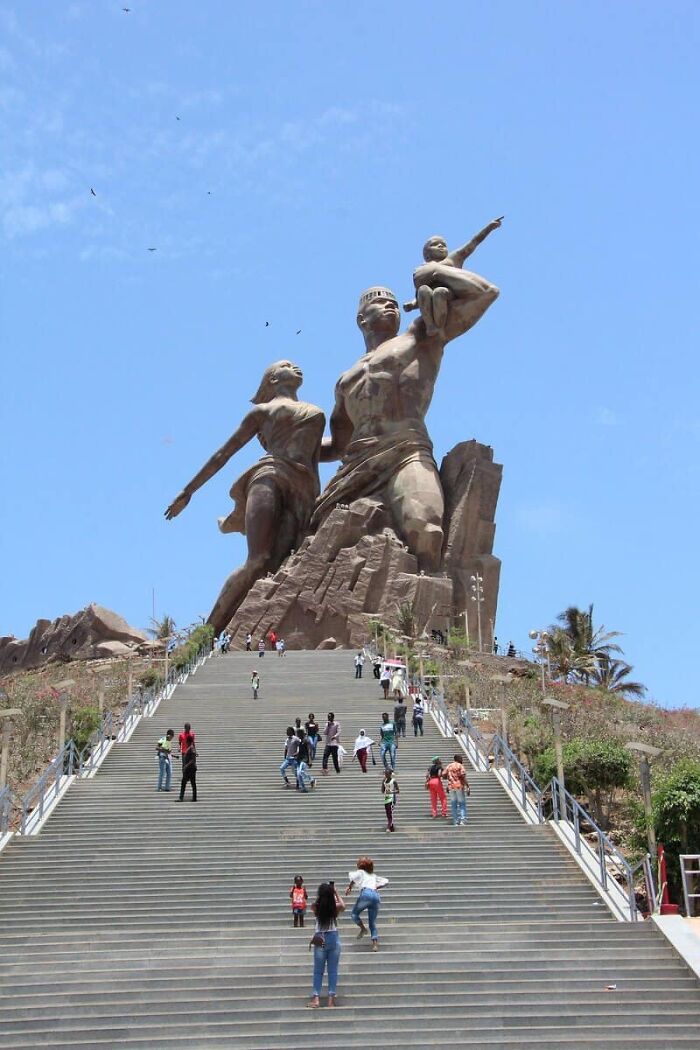 A massive bronze statue, The African Renaissance Monument, depicting a man, woman, and child, showing the true scale.