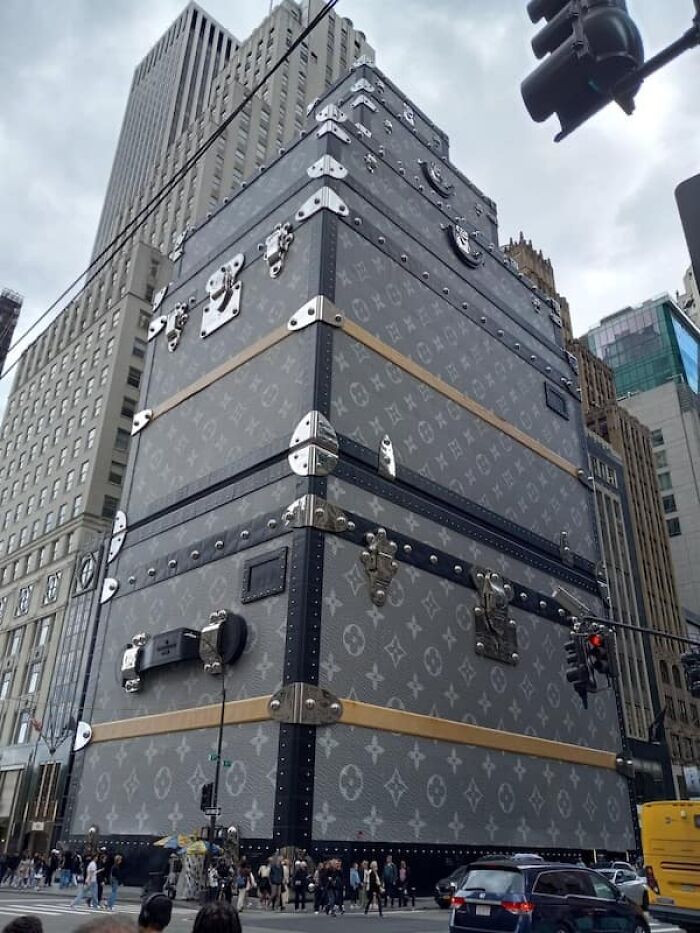 Giant Louis Vuitton luggage cases stacked high in a city street, illustrating true scale of objects.