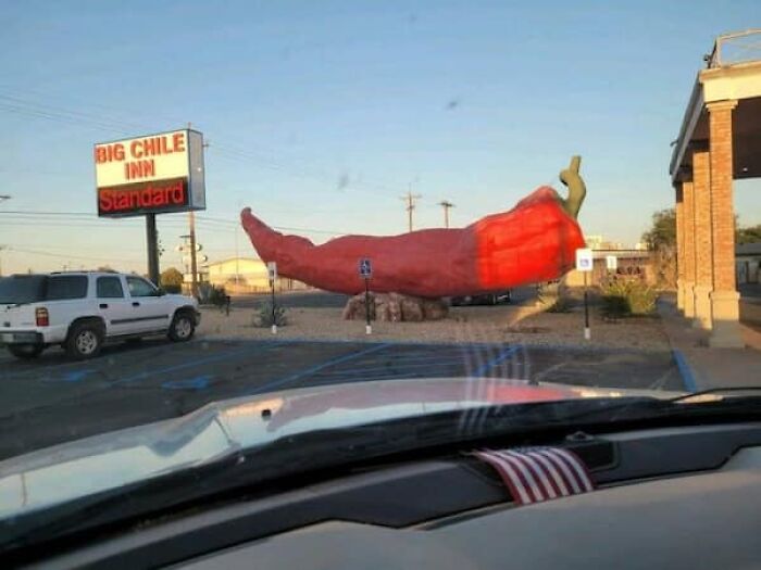 A huge red chili pepper sculpture in front of the Big Chile Inn, demonstrating the true scale of roadside attractions.