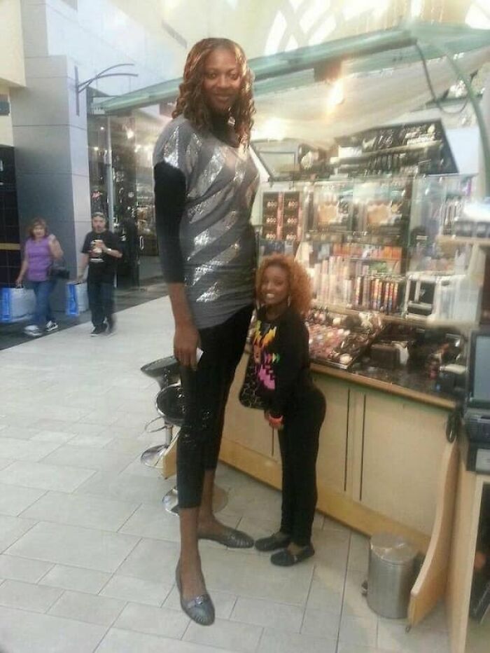 A striking size comparison of a very tall woman standing next to a much shorter woman, illustrating their true scale.