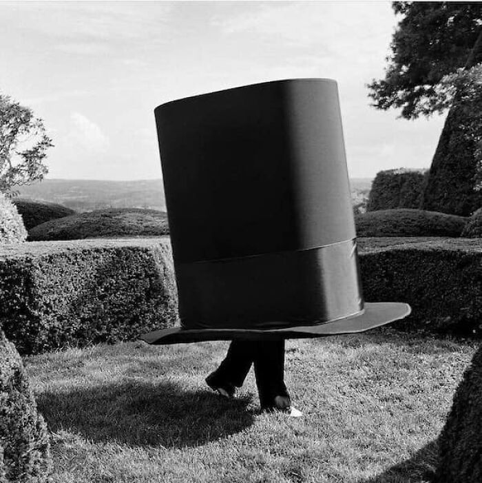 A person walking with an enormous top hat covering their entire body, showcasing a humorous size comparison.