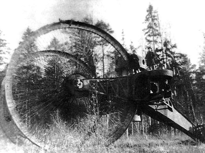A massive, wheeled vehicle in a forest, showing the true scale of the Tsar Tank with people standing on it.