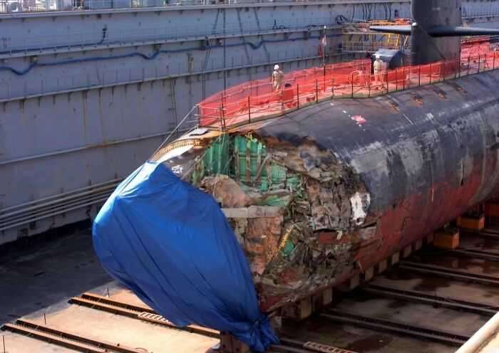 A damaged submarine in drydock, revealing the true scale of its internal size comparison with exposed parts.