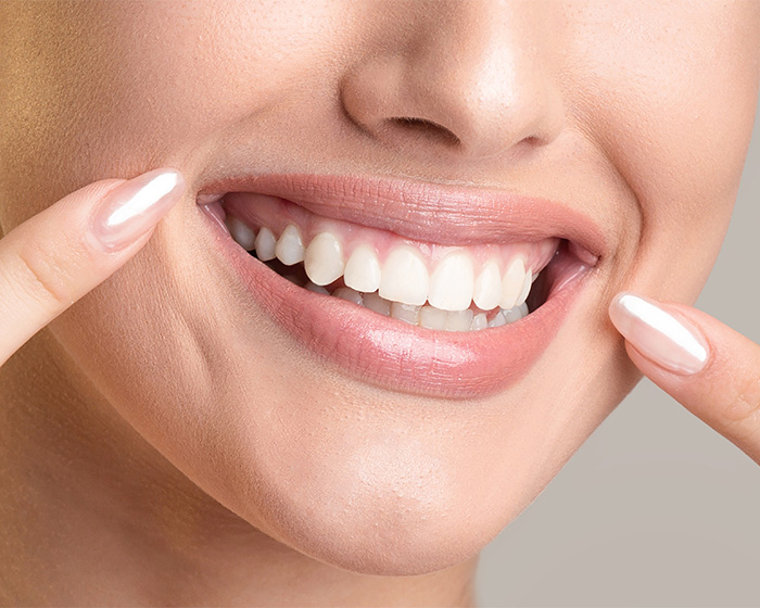 Close-up of a white smile, fingers pointing at teeth. Experts discuss African twig alternatives to toothpaste. Close-up of a white smile, fingers pointing at teeth. Experts discuss African twig alternatives to toothpaste.