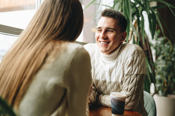 A smiling man talking to a woman, unknowingly showing subtle signs someone isn't as nice as they pretend to be.