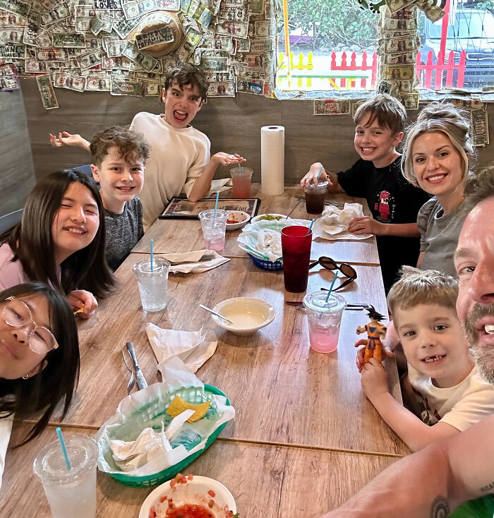 Smiling Michigan family, including kids and parents, at a restaurant table, before tragic events. Michigan Man.