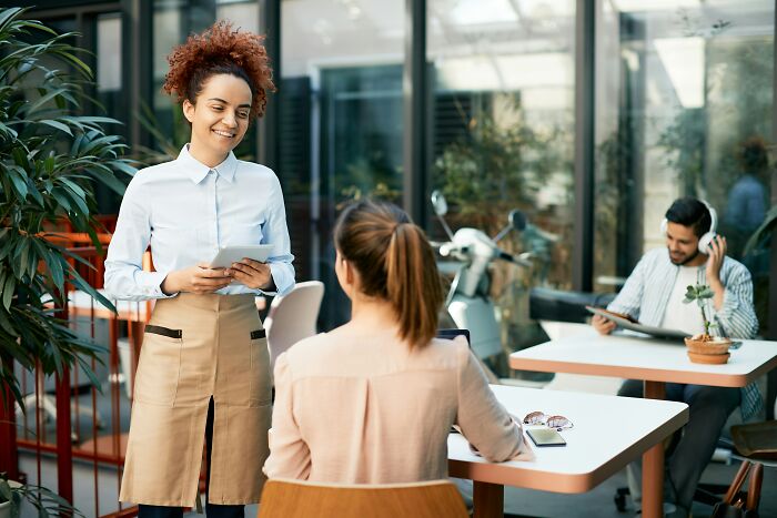 A waitress takes an order in a cafe; avoiding a socially awkward encounter.