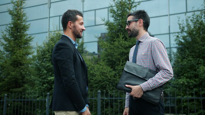 Two socially awkward men having a conversation outdoors, highlighting a cringe moment.