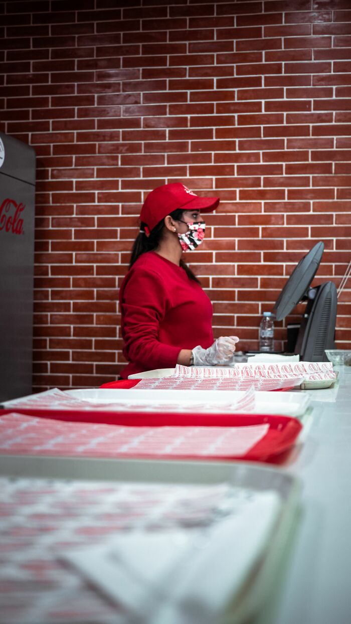 A restaurant worker, possibly feeling socially awkward, standing behind the counter, creating cringe moments.
