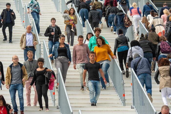 Crowds of people walk up and down large stairs; navigating a potentially socially awkward crowd.