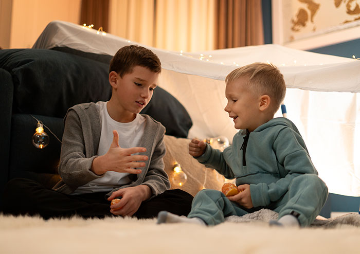 Two young brothers playing inside a blanket fort, highlighting the responsibility to raise kids. Two young brothers playing inside a blanket fort, highlighting the responsibility to raise kids.