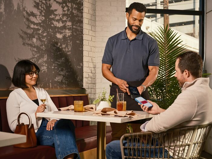 A couple making a payment at a restaurant, potentially experiencing culture shocks with international partners.