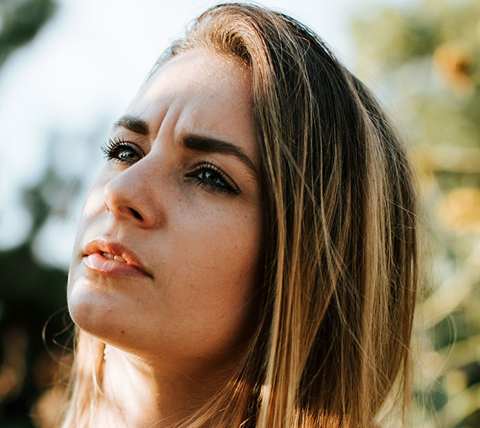 A woman looking away, contemplating satisfying cases of instant karma shared by divorce lawyers.