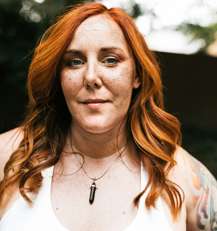 A woman with red hair looking directly at the camera, sharing insights on instant karma from divorce lawyers.
