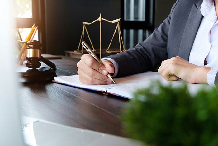 A divorce lawyer writing at a desk with scales of justice and a gavel, detailing cases of instant karma.