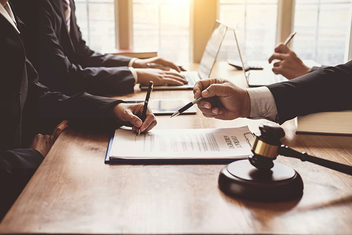 Divorce lawyers at a table, signing documents, discussing instant karma in their most satisfying cases.