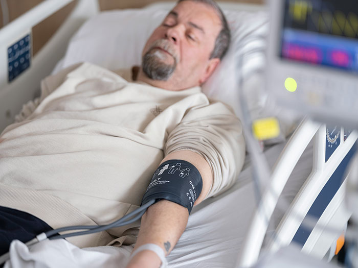 A man in a hospital bed, being monitored, a possible consequence of instant karma.
