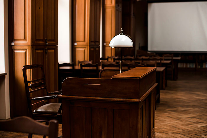 A divorce lawyer's perspective on instant karma, showing an empty courtroom with wooden furniture and a lamp.