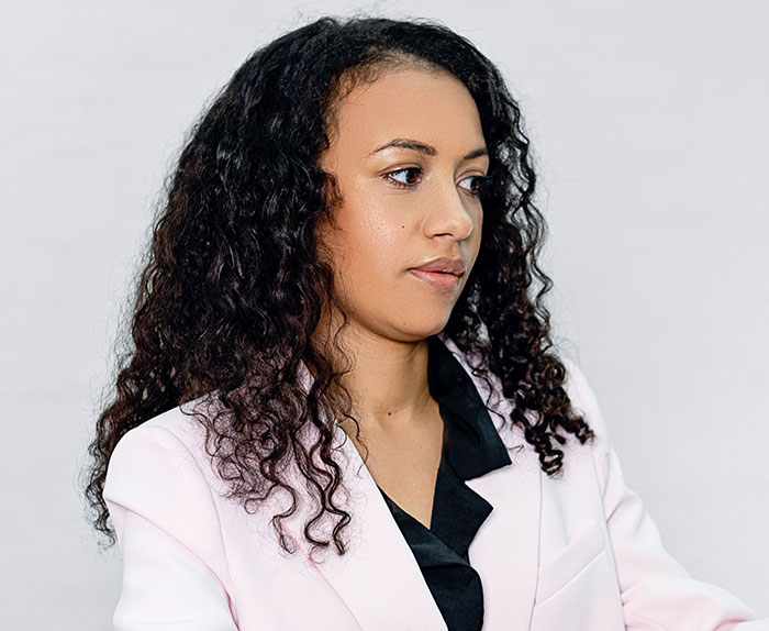 A young female divorce lawyer with curly hair, contemplating past instant karma cases.