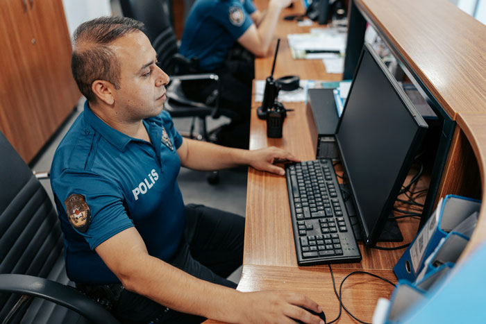 Police officer at a desk, likely involved in investigation of a spy camera in room incident with a step dad. Police officer at a desk, likely involved in investigation of a spy camera in room incident with a step dad.
