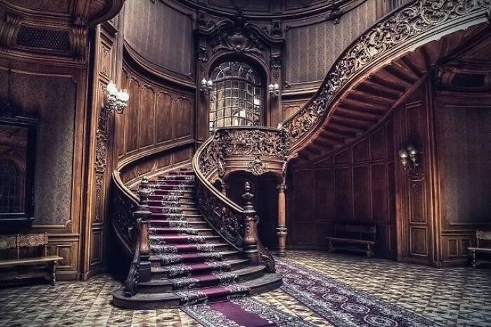 Remarkable historic interiors: a grand wooden staircase with intricate carvings, showcasing iconic furniture designs.