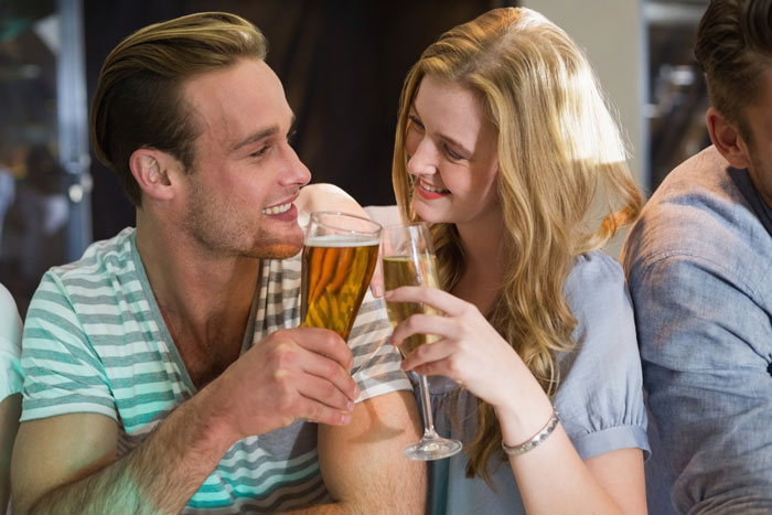 Young couple toasting beer and champagne, thinking about the age to give up beer for nervous system.