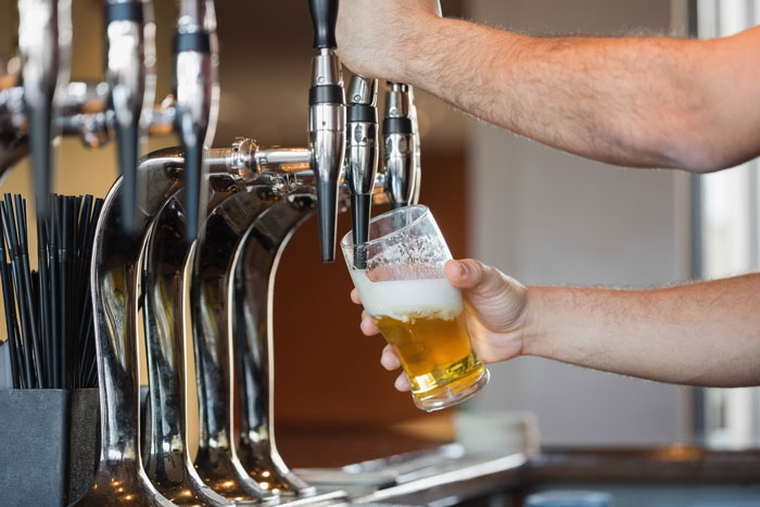 Bartender pouring a beer, contemplating the age to give up beer for nervous system health.