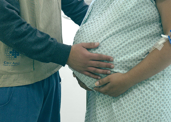 A partner's hands gently caressing a pregnant belly, highlighting human body facts and medical student interest.
