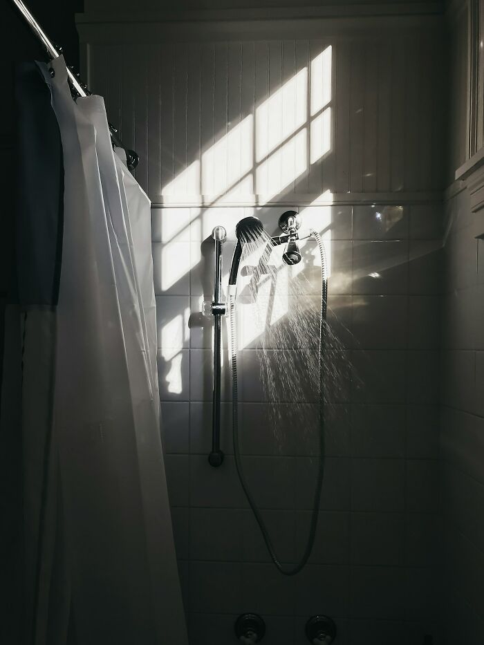 Sunlight streams through a bathroom window, illuminating water spraying from a showerhead, highlighting unusual ways people lost lives.