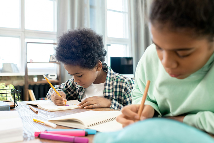Two young students, a boy and a girl, focusing on writing in their notebooks, getting revenge. Two young students, a boy and a girl, focusing on writing in their notebooks, getting revenge.