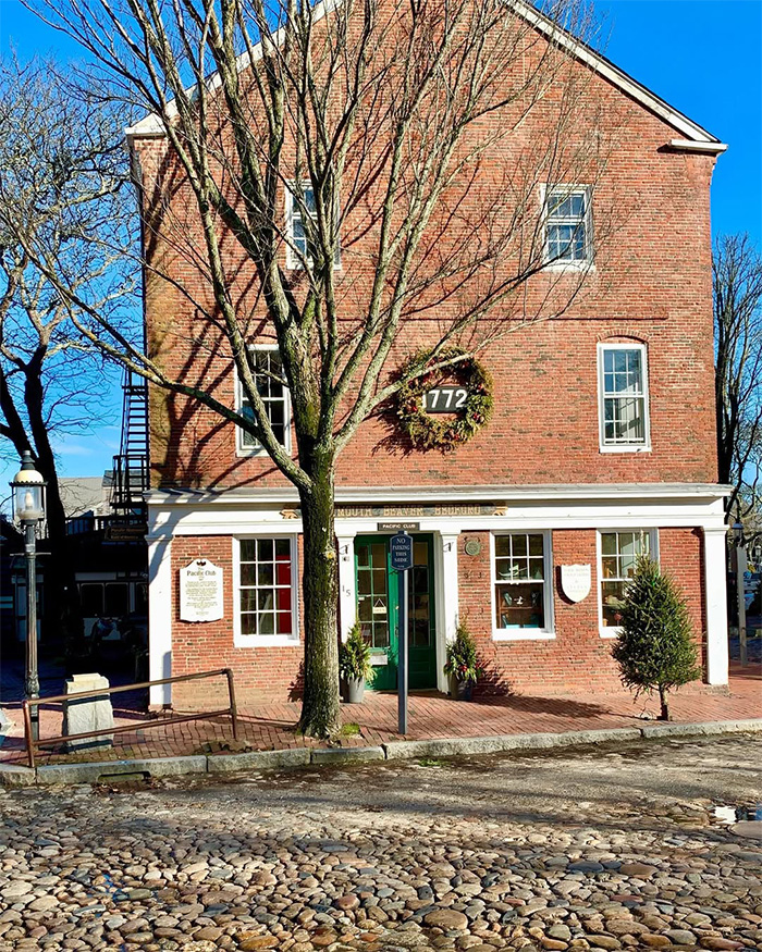 Historic brick building in Nantucket with large wreath and cobblestone street