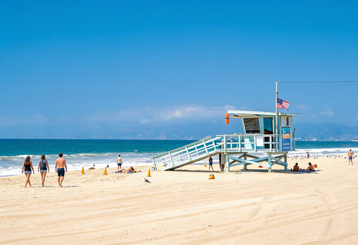 People on a sunny beach with a lifeguard station, reflecting on stopping work in the heat.