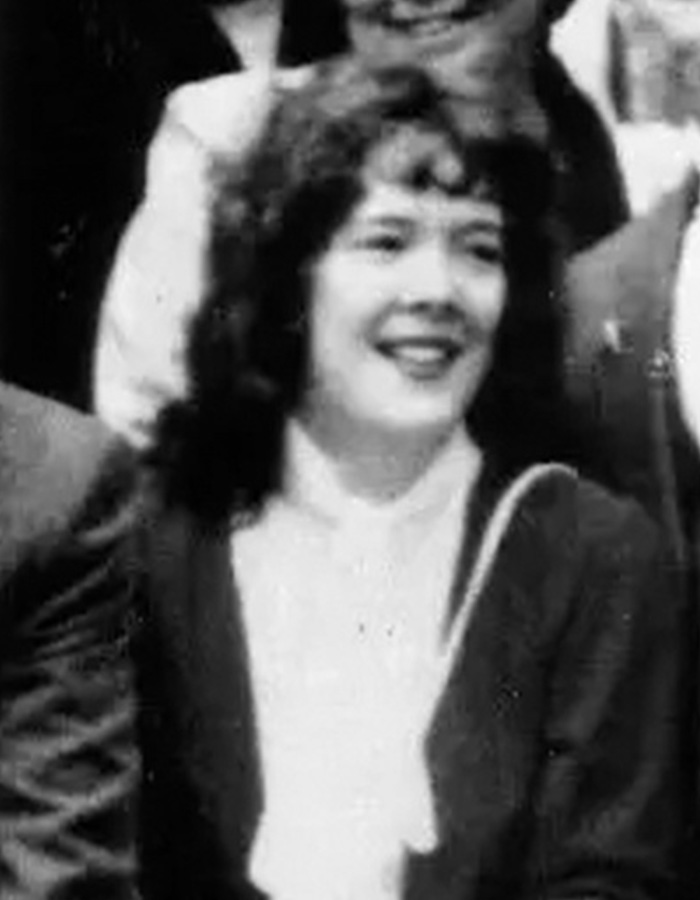 A black and white photo of a smiling woman.