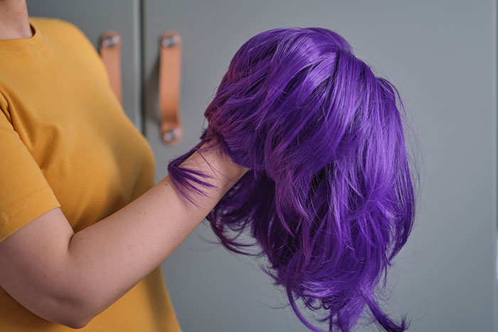 Stepmom holding a purple K-Pop character wig for a kid's birthday party. Stepmom holding a purple K-Pop character wig for a kid's birthday party.